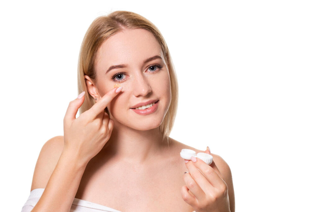 Close-up of a person's hand applying eye cream to the under-eye area.